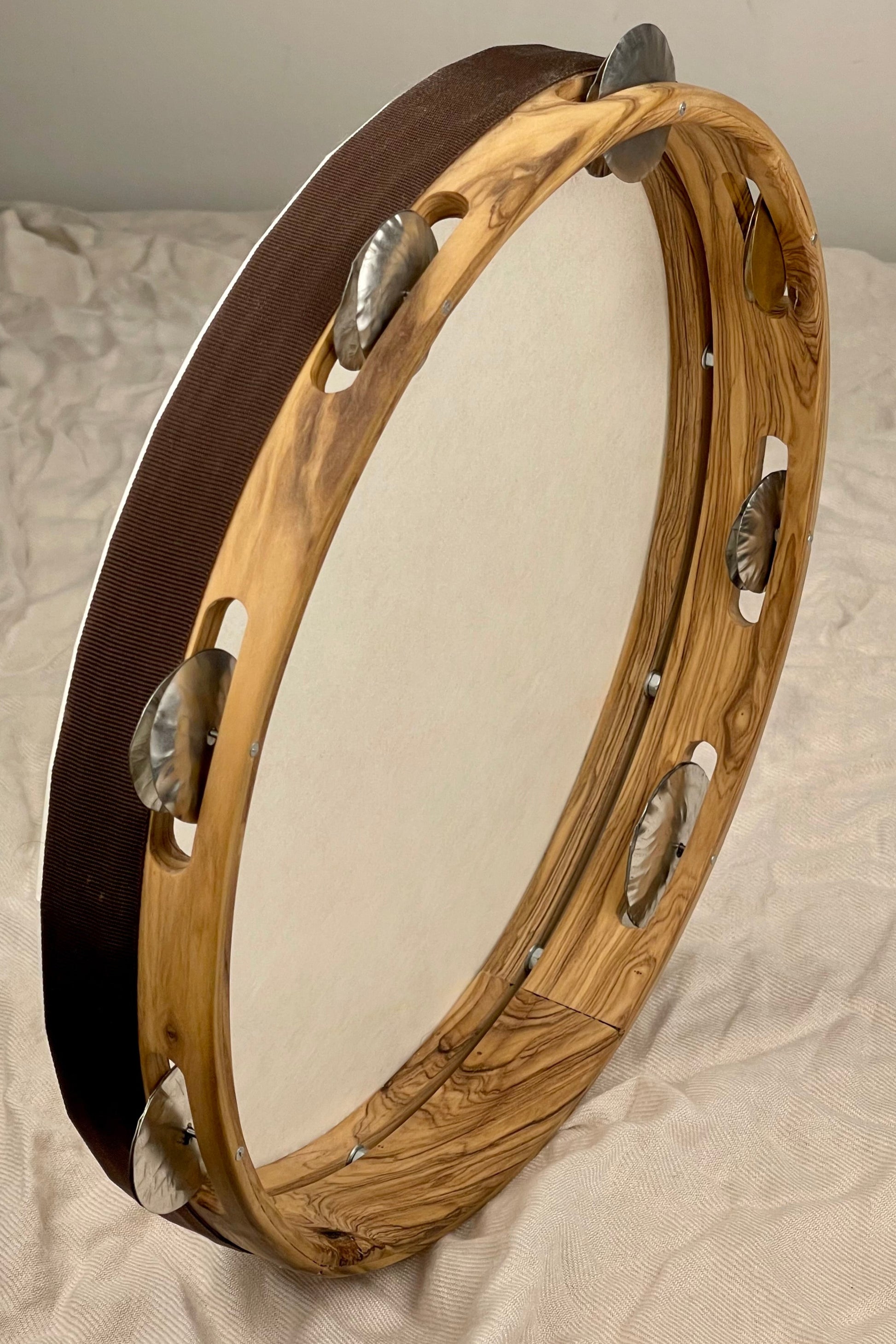 Side view of solid olive wood tambourine with wax finish and textured head