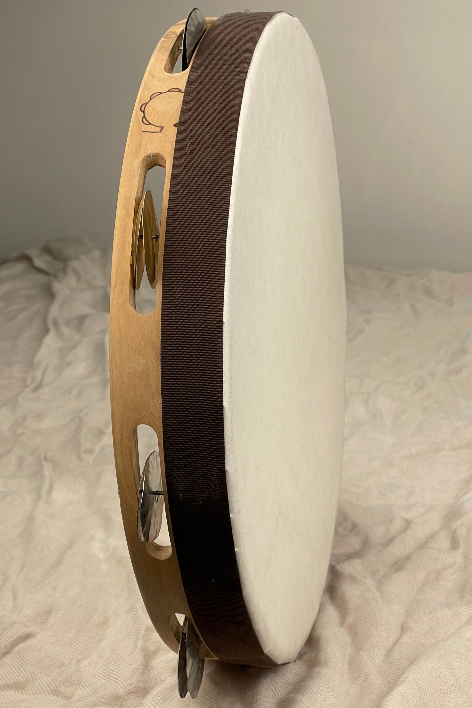 Side view of solid olive wood tambourine with wax finish and textured head